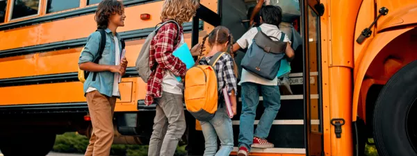 Five kids getting onto the school bus in the morning