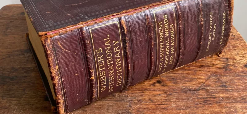 Very old Websters Dictionary sitting on a tabletop